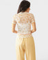 Woman wearing a floral top and yellow checkered pants on a white background