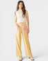 Woman wearing a floral top and yellow checkered pants with pink accents on a white background