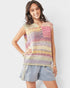 Woman wearing a colorful crochet sleeveless top with denim shorts on a white background