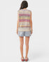 Woman wearing a sleeveless, multicolored knit top and light blue shorts on a white background