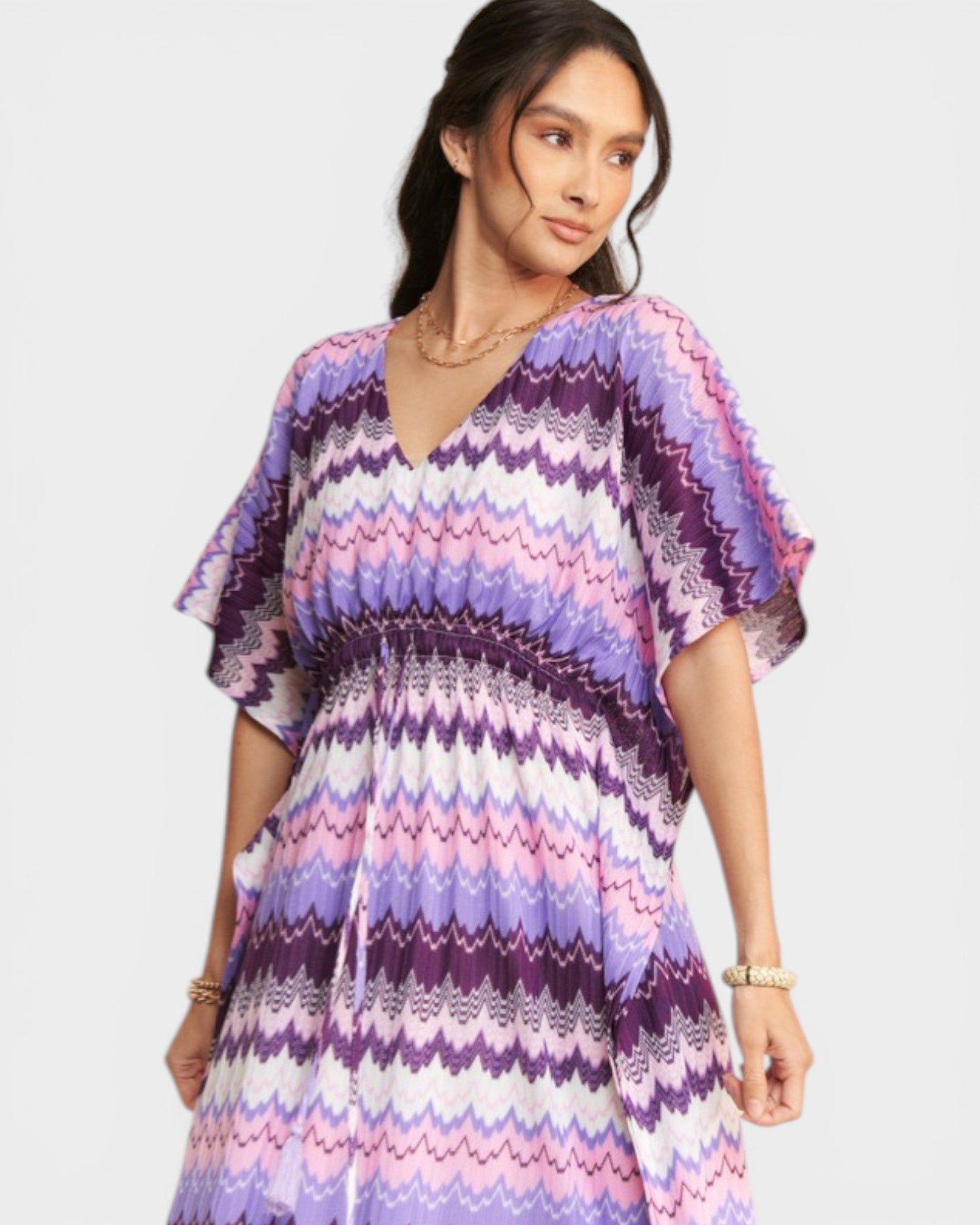 Woman wearing a colorful zigzag patterned dress on a light gray background