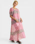 Woman wearing a pink and brown patterned dress on a white background