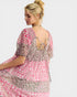Woman wearing a pink and patterned dress on a white background