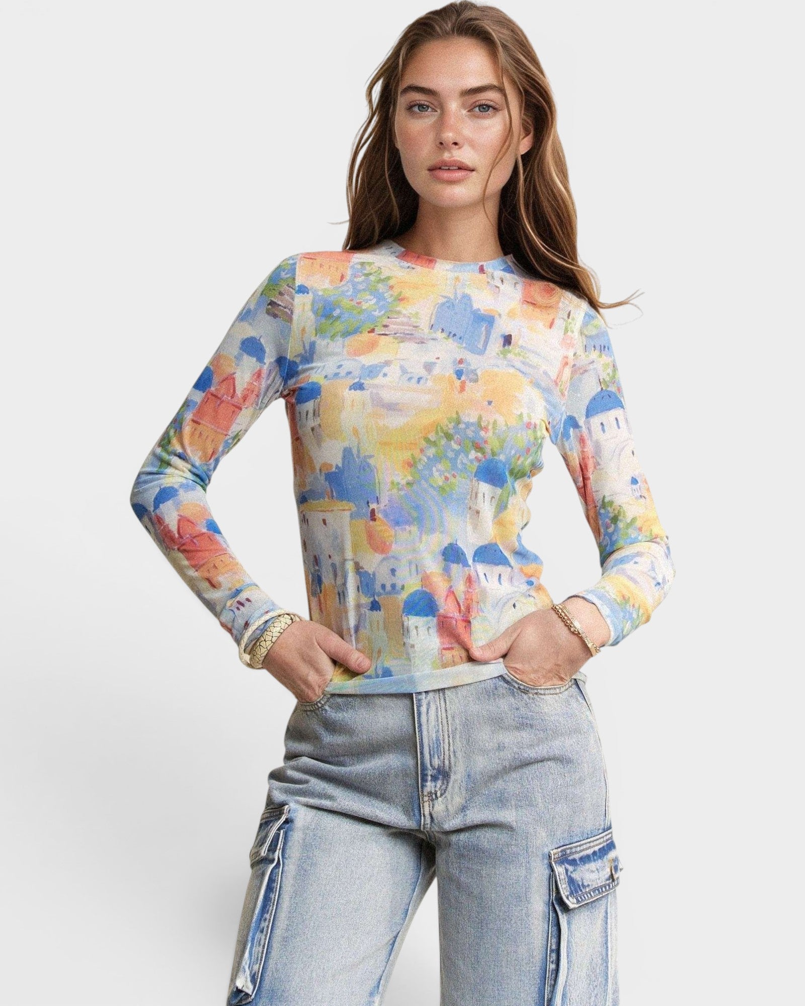 Woman wearing a colorful long-sleeve top with a pattern of buildings and blue jeans on a white background