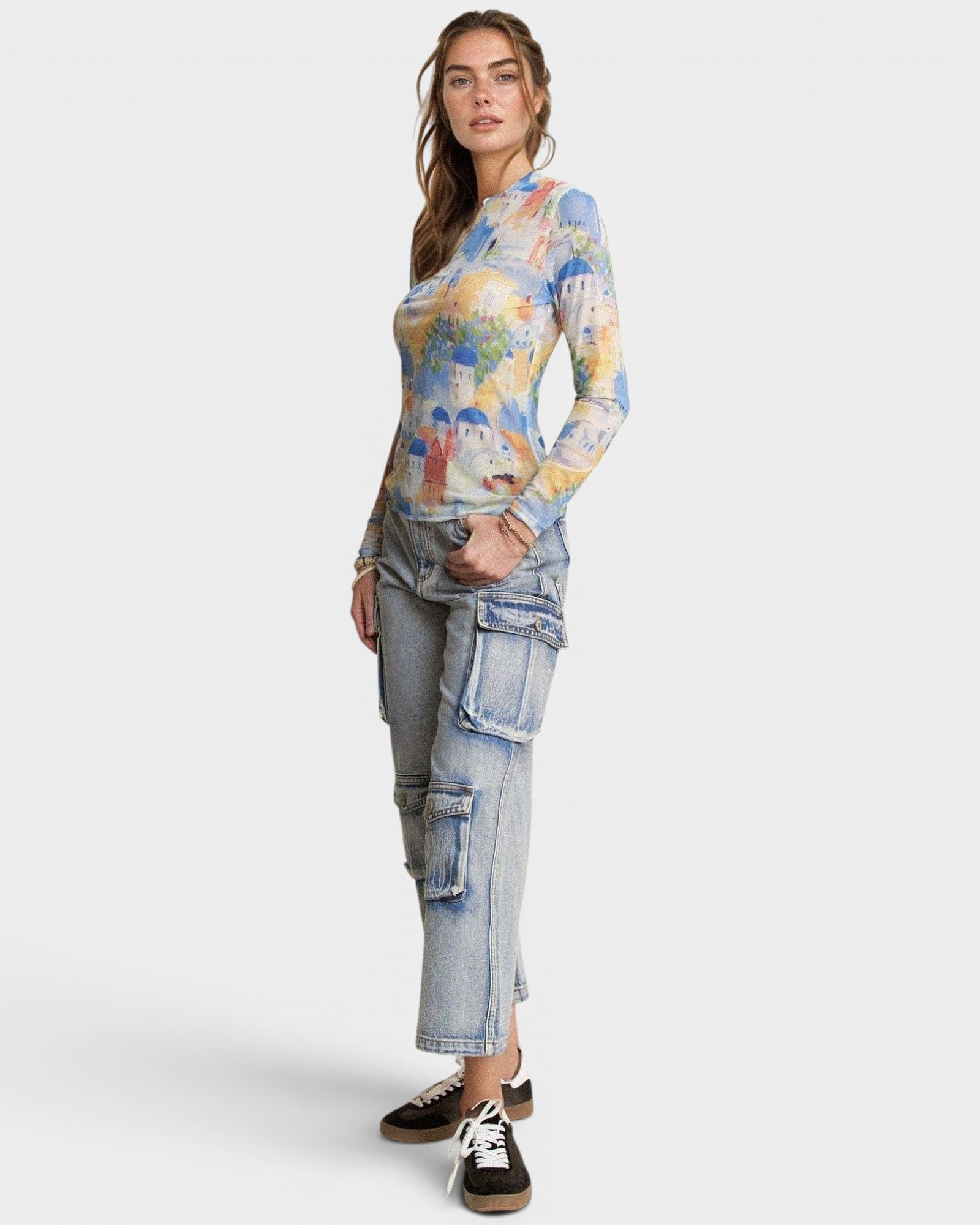 Woman wearing a colorful long-sleeve top and light blue cargo pants on a white background