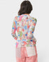 Person wearing a colorful patterned top and pink pants on a white background