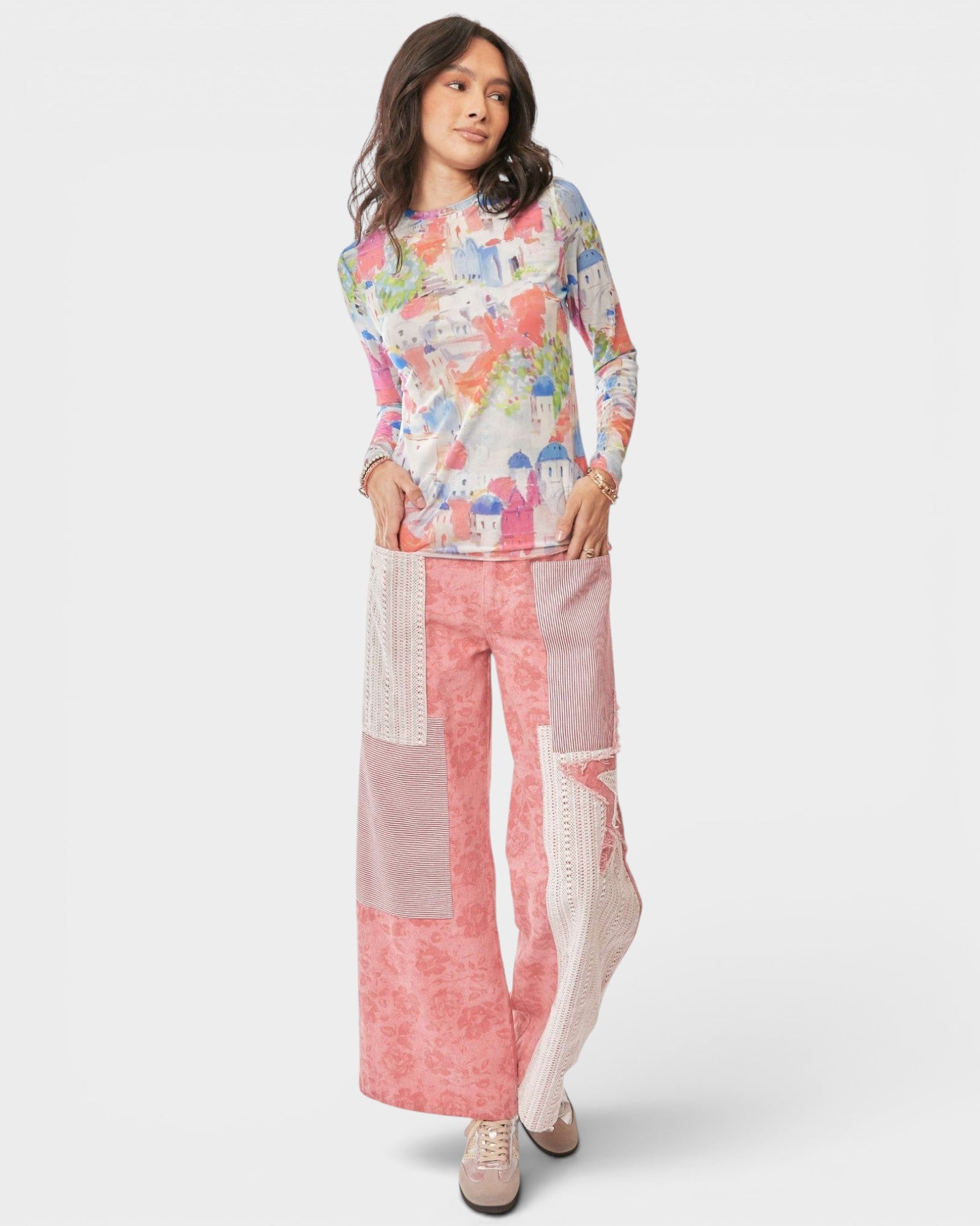Woman wearing a colorful top and pink patchwork pants on a white background