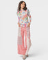 Woman wearing a colorful top and pink patchwork pants on a white background