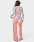 Woman wearing a colorful patterned jacket and pink pants on a white background