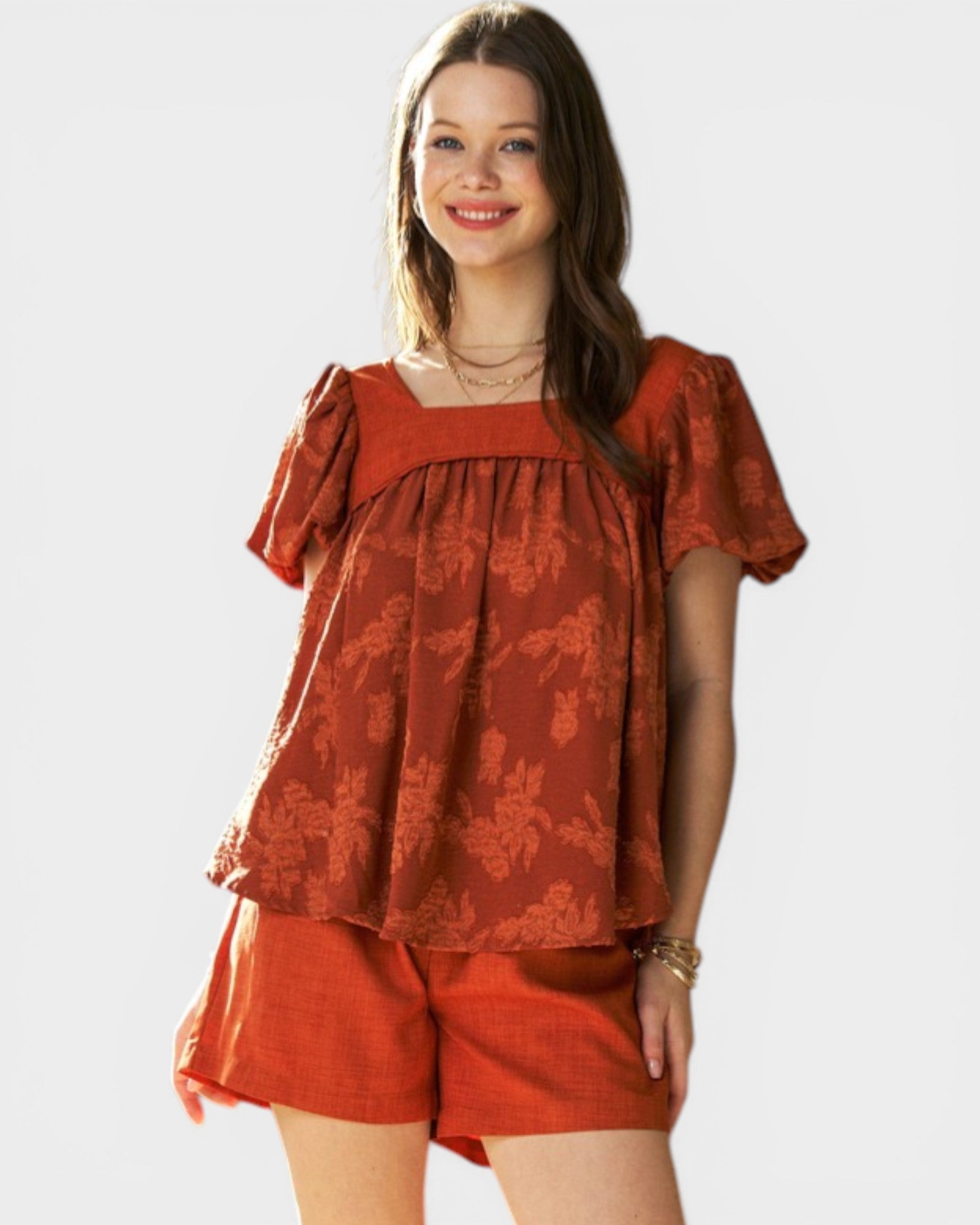 Woman wearing a red patterned top and shorts on a white background