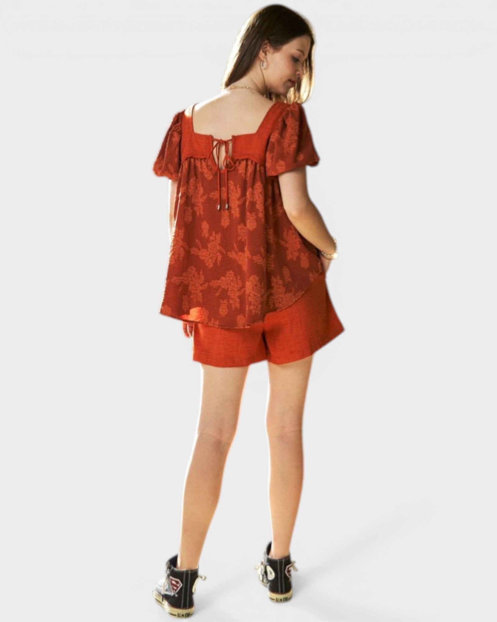Woman wearing a red floral top and shorts on a white background