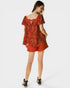 Woman wearing a red floral top and shorts on a white background