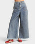 Wide-leg jeans worn with red sneakers on a white background