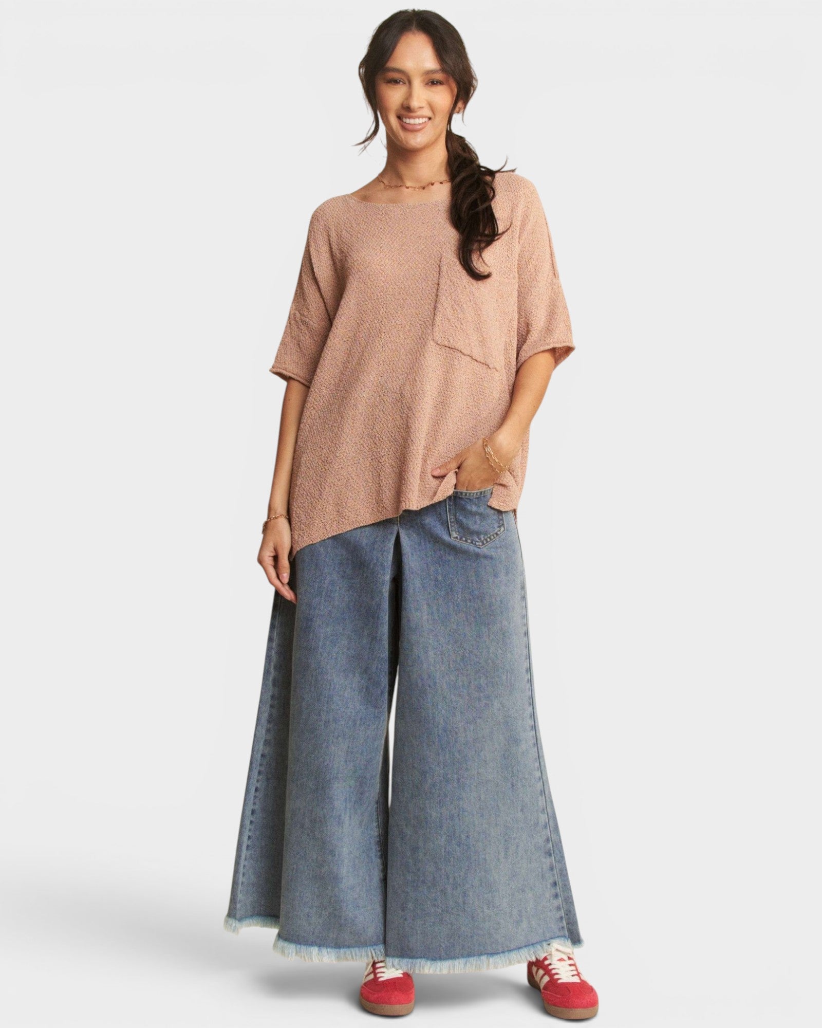 Woman wearing a beige top and blue jeans on a white background