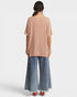 Person wearing a beige top and blue jeans on a white background