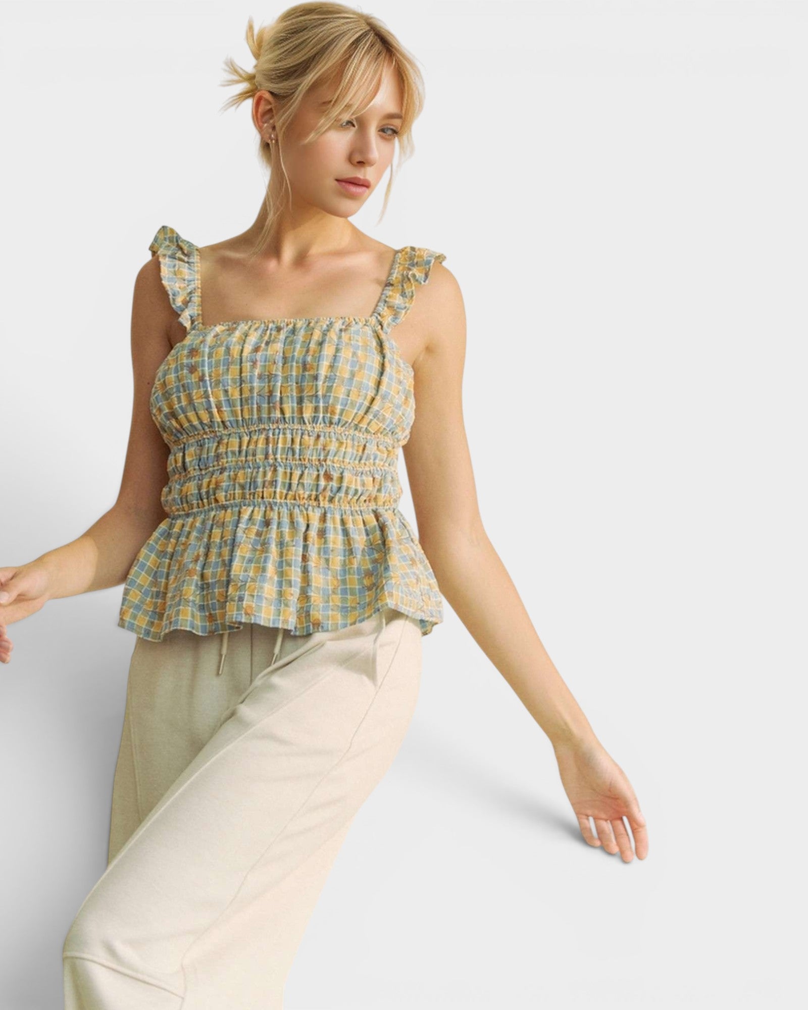 Woman wearing a checkered top and beige pants on a plain background