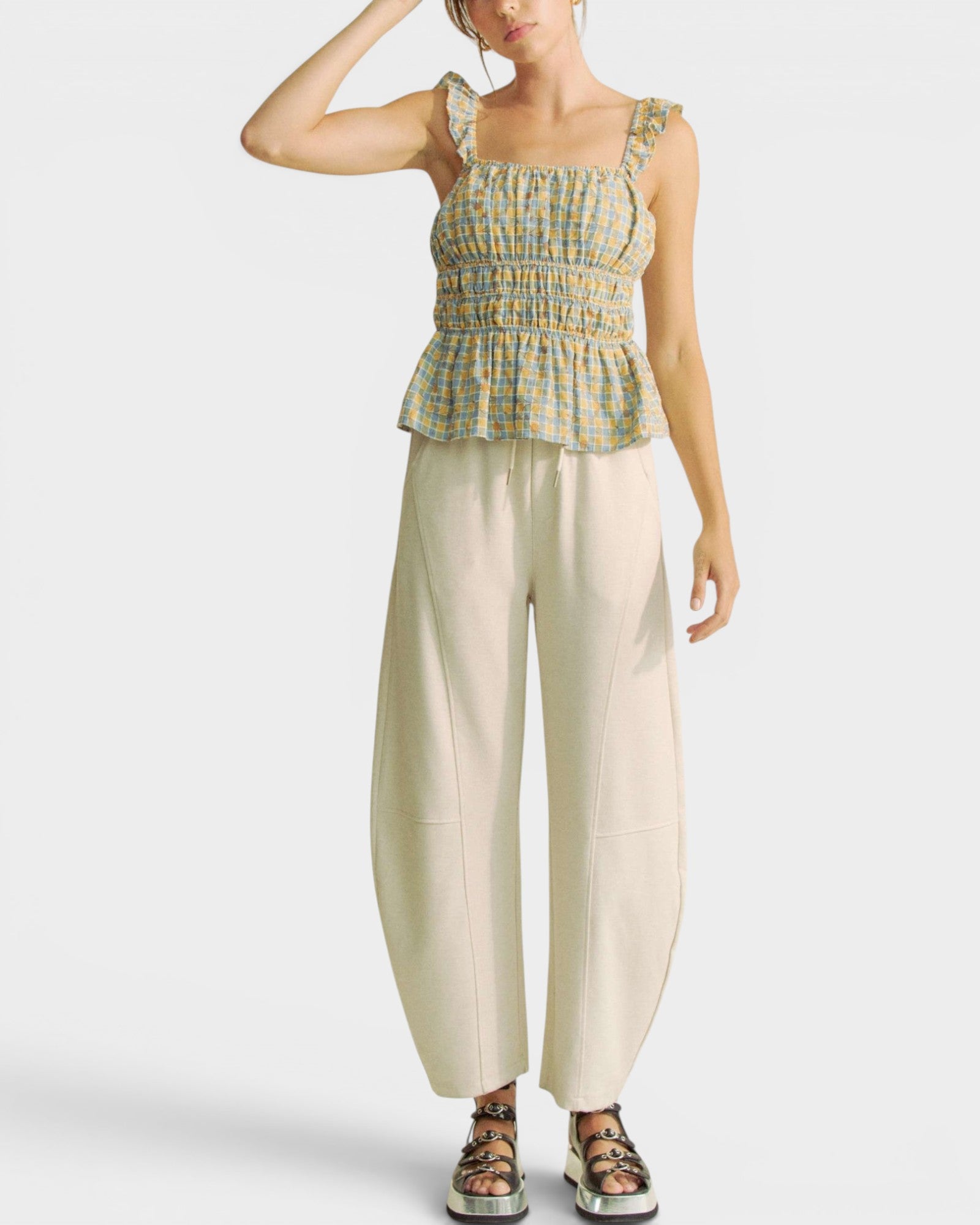 Woman wearing a checkered top and beige pants on a white background