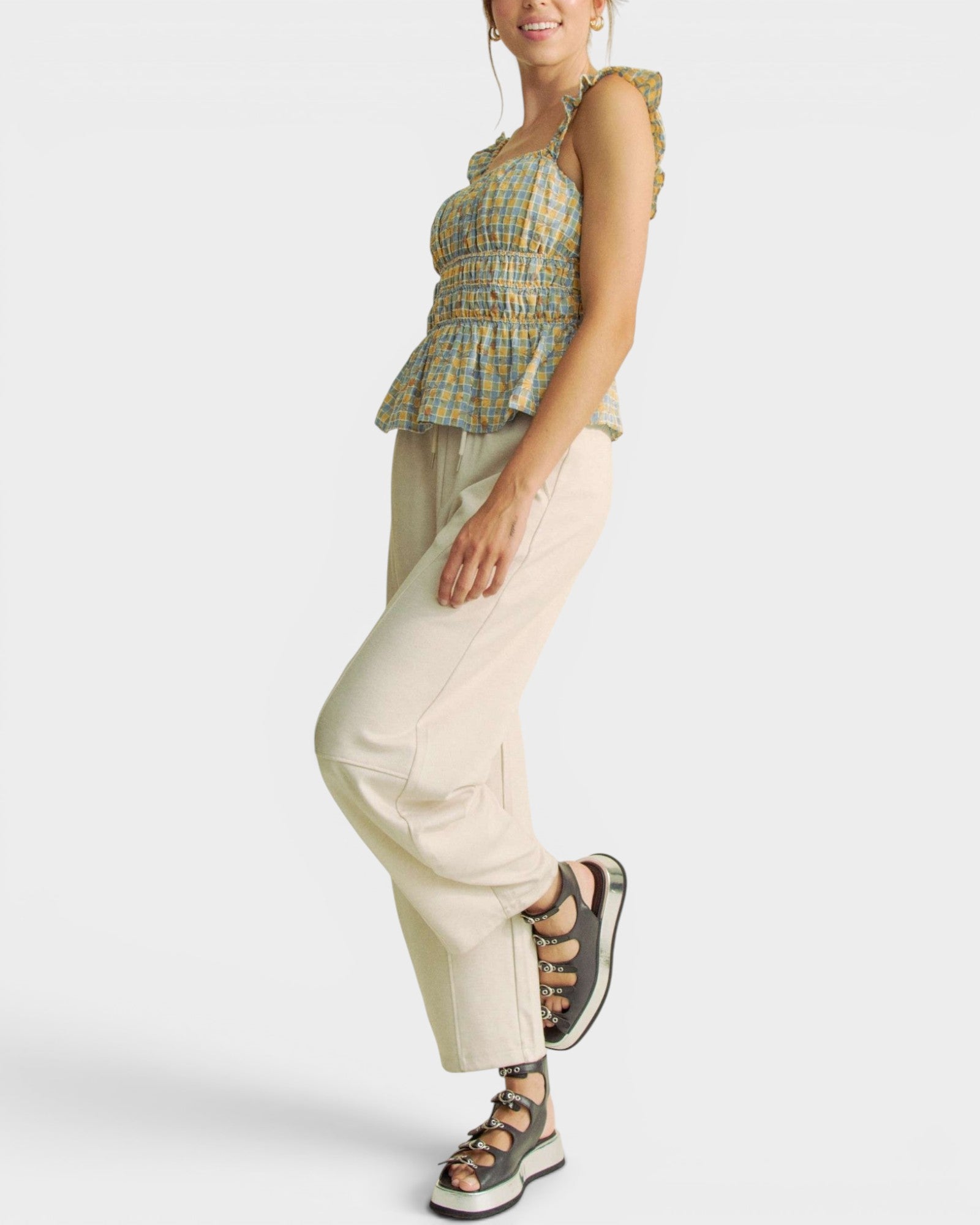 Woman wearing a plaid top and beige pants on a white background