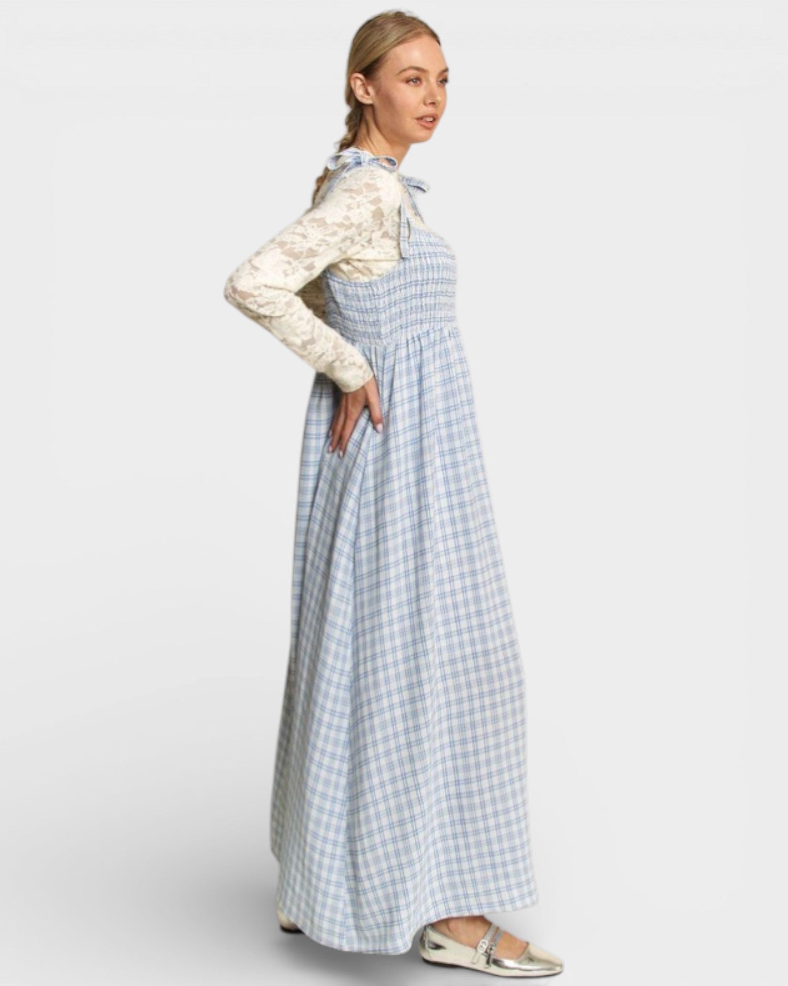 Woman wearing a white blouse and blue checkered dress on a light gray background