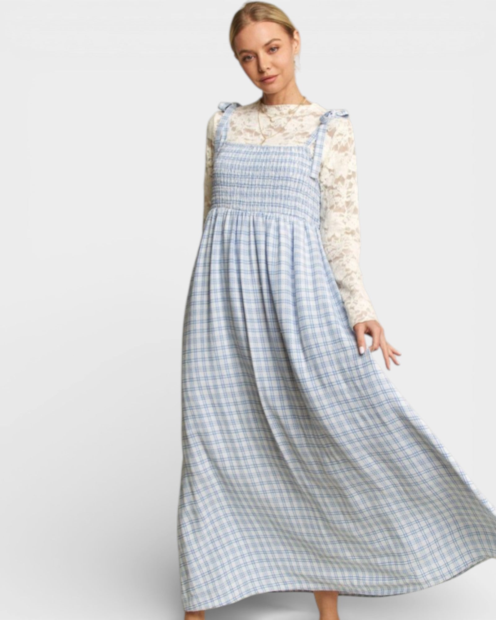 Woman wearing a blue checkered dress with a white lace top on a light gray background
