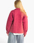 A woman shown from the back wearing a quilted pink jacket, light blue jeans, and a white t-shirt, against a plain white background.