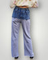 Person wearing blue jeans and a colorful top on a plain background