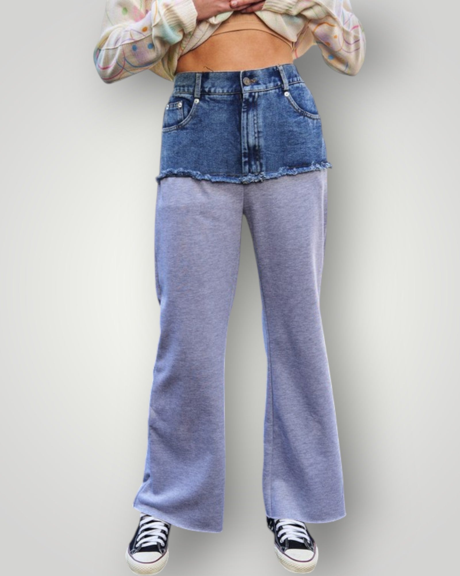 Person wearing blue flared jeans and a patterned shirt on a plain background