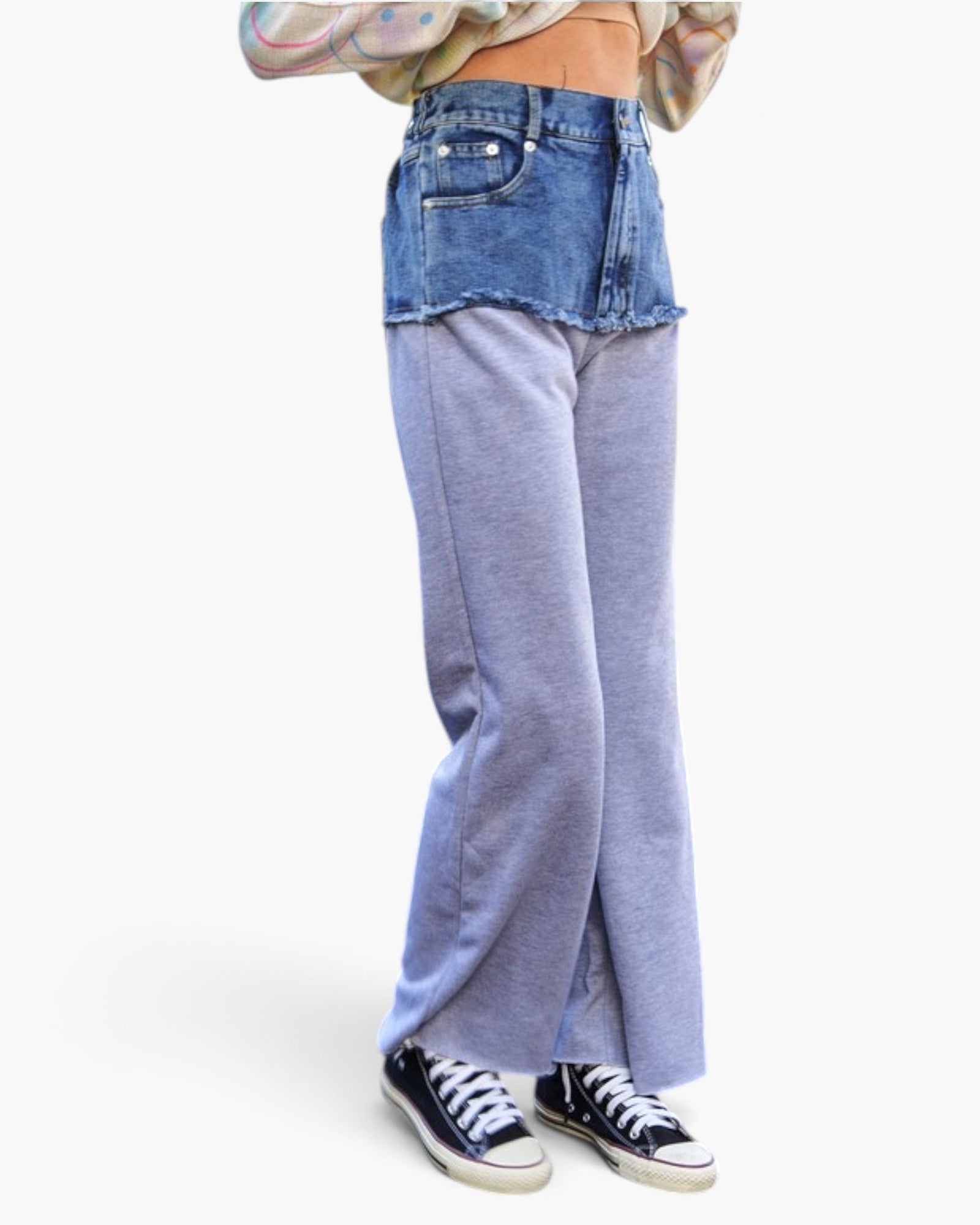 A person shown from the waist down wearing layered pants with a blue denim top half and light blue heathered wide-leg bottom half, paired with black sneakers against a plain white background.