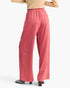 A person shown from the back wearing loose, wide-leg pink pants with a small side embellishment and a tan top, photographed against a plain light background.