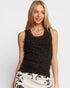Woman wearing a black sleeveless top with white polka dots on a plain background