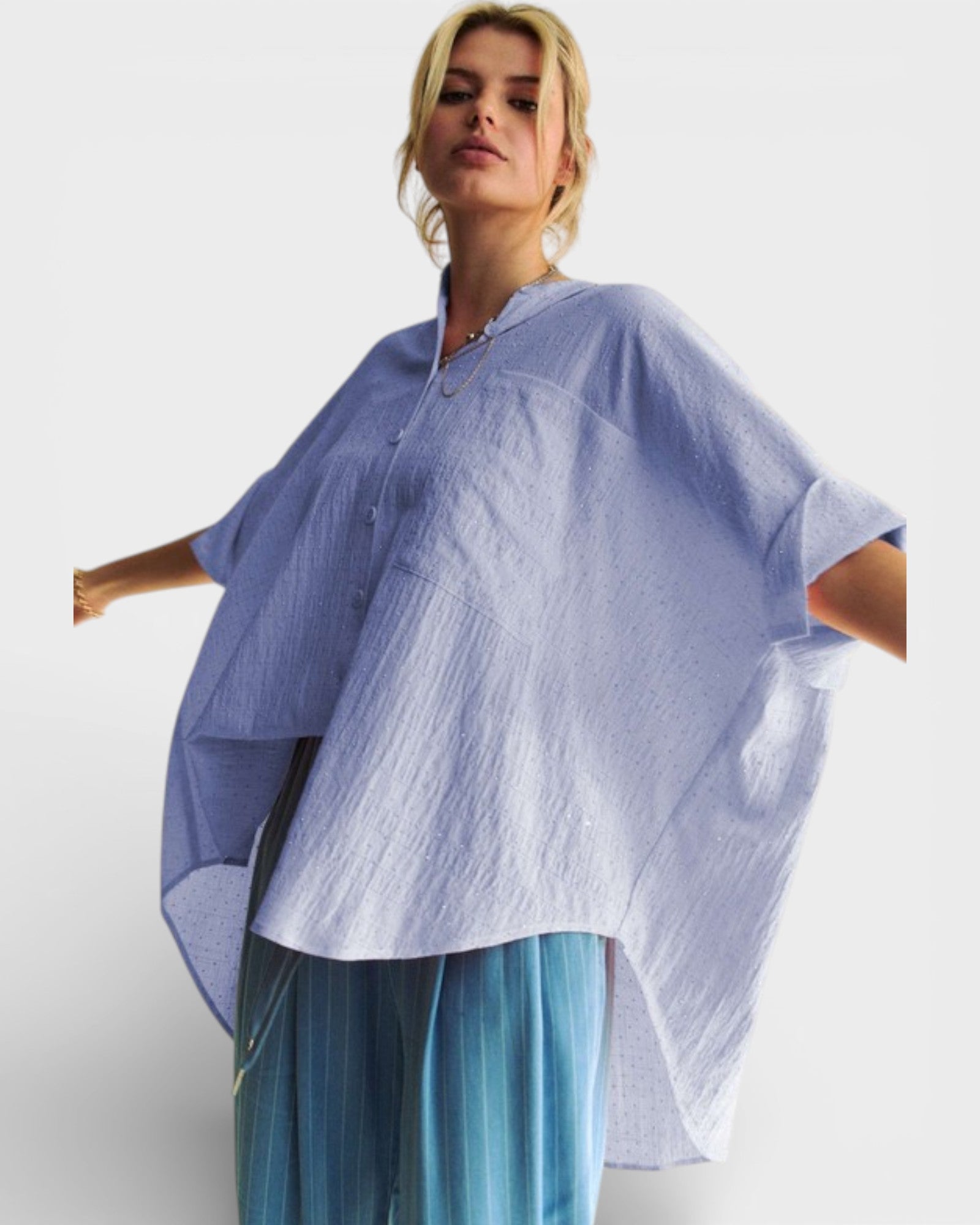 Woman wearing a light blue poncho over a white background