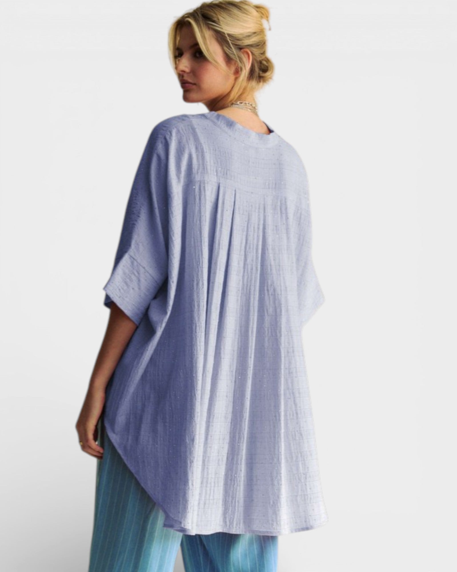 Woman wearing a light blue and white striped dress against a white background