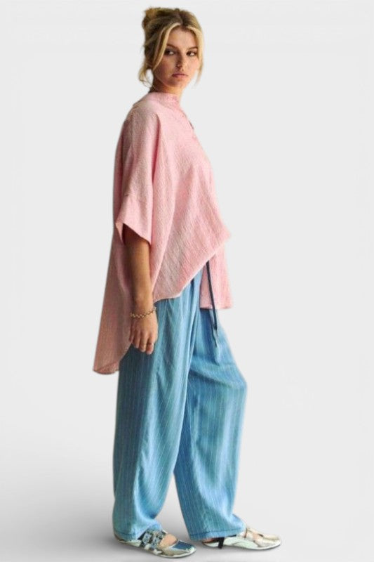 Person wearing a pink top and blue pants on a white background