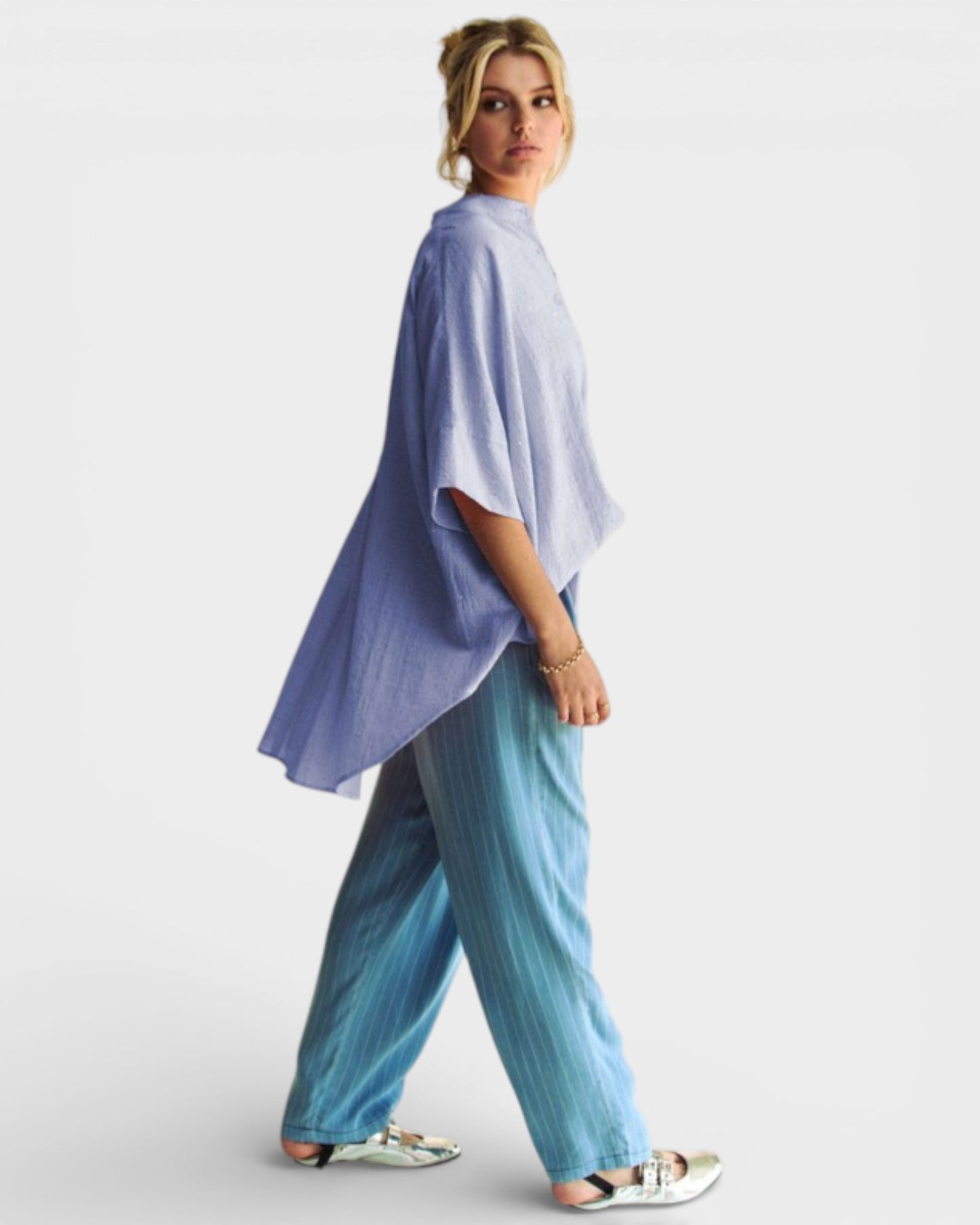 Woman wearing a light blue poncho and pants on a white background