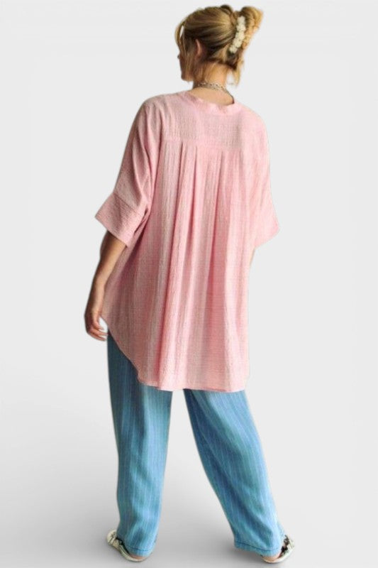 Person wearing a pink oversized shirt and blue pants on a white background