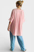 Person wearing a pink oversized shirt and blue pants on a white background