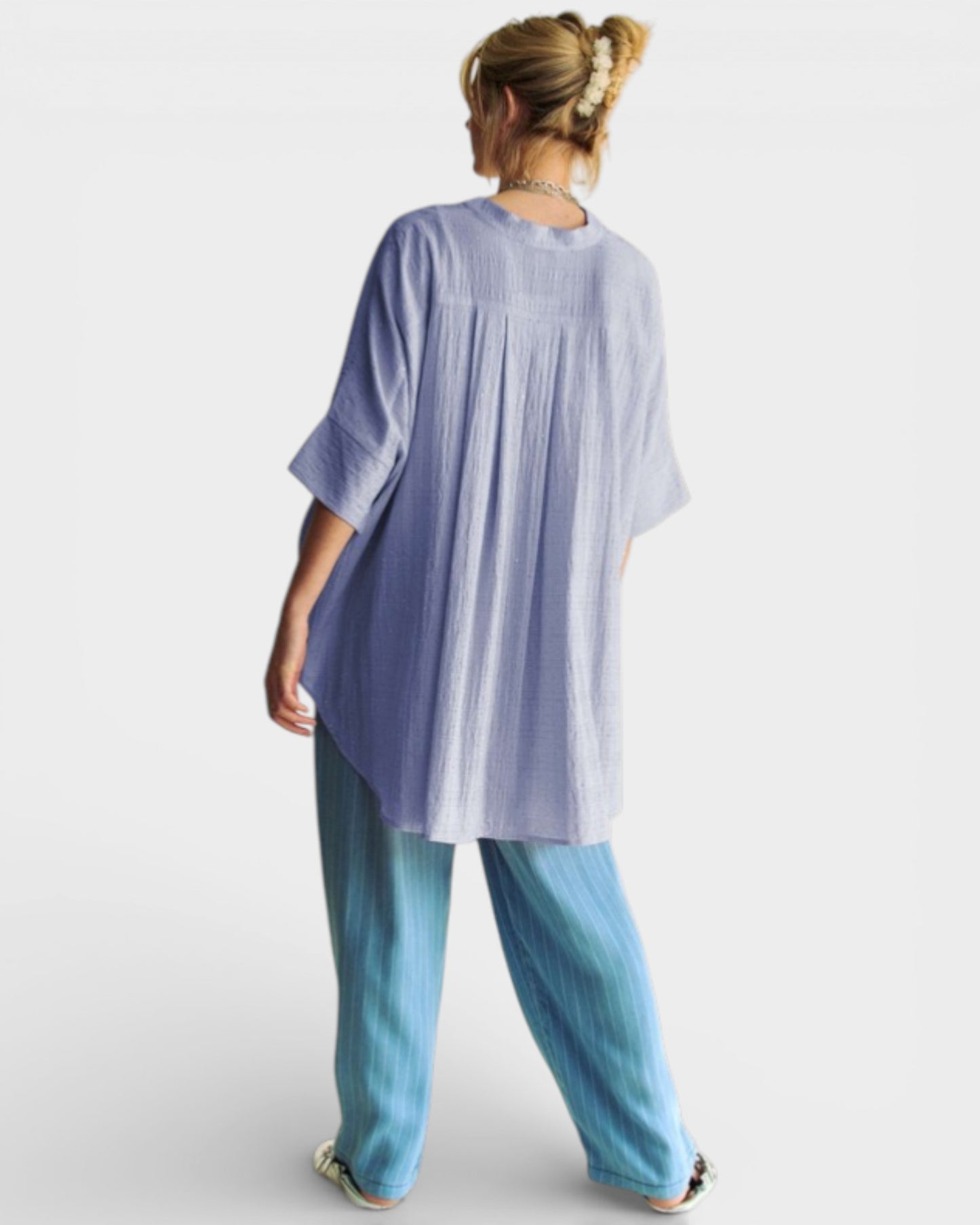 Person wearing a light blue oversized shirt and jeans on a white background