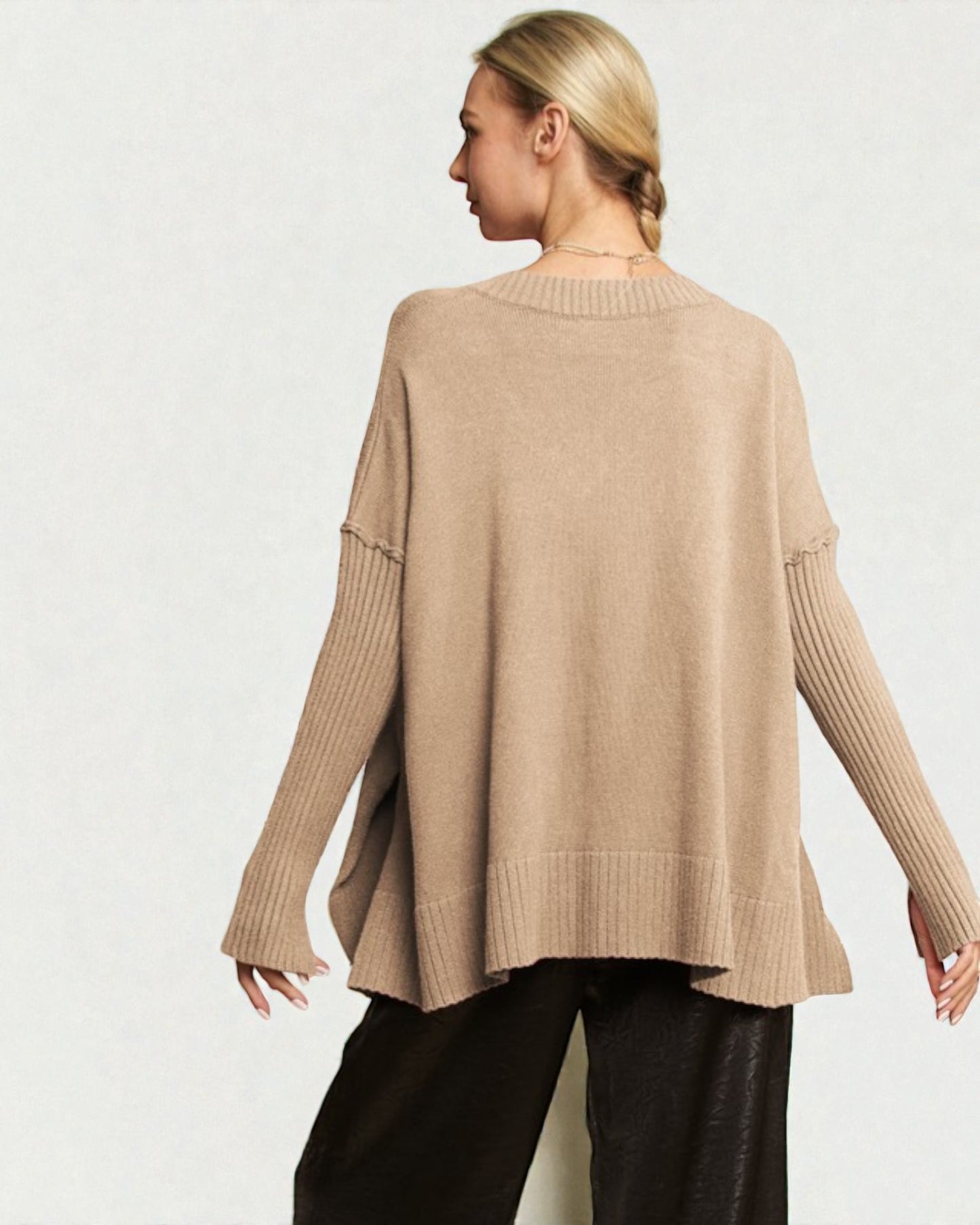 Woman wearing a beige sweater and black pants on a white background