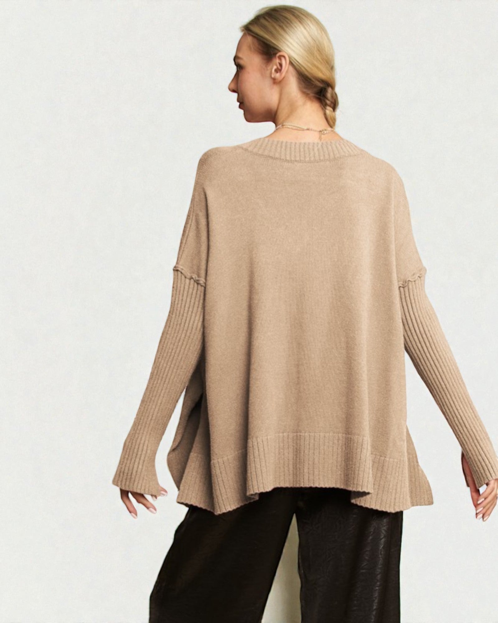 Woman wearing a beige sweater and black pants on a white background