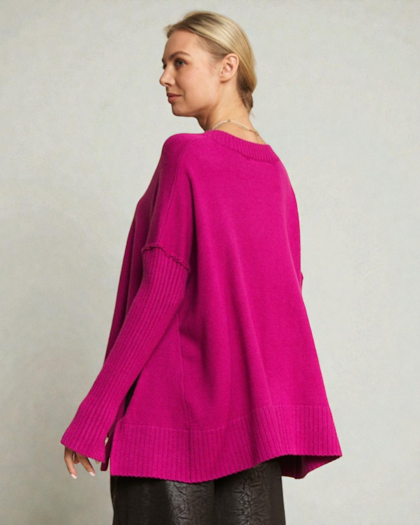 Woman wearing a bright pink sweater against a plain background