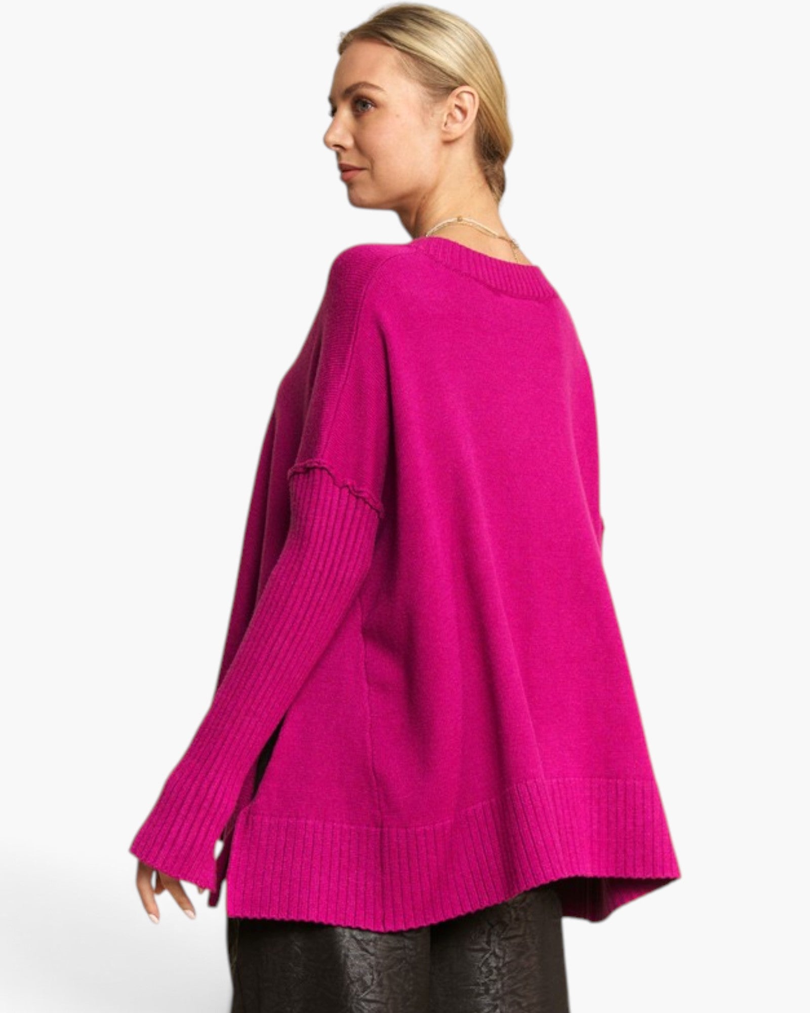 A woman wearing a bright magenta pink knit sweater, shown from a side-back angle against a clean white background.