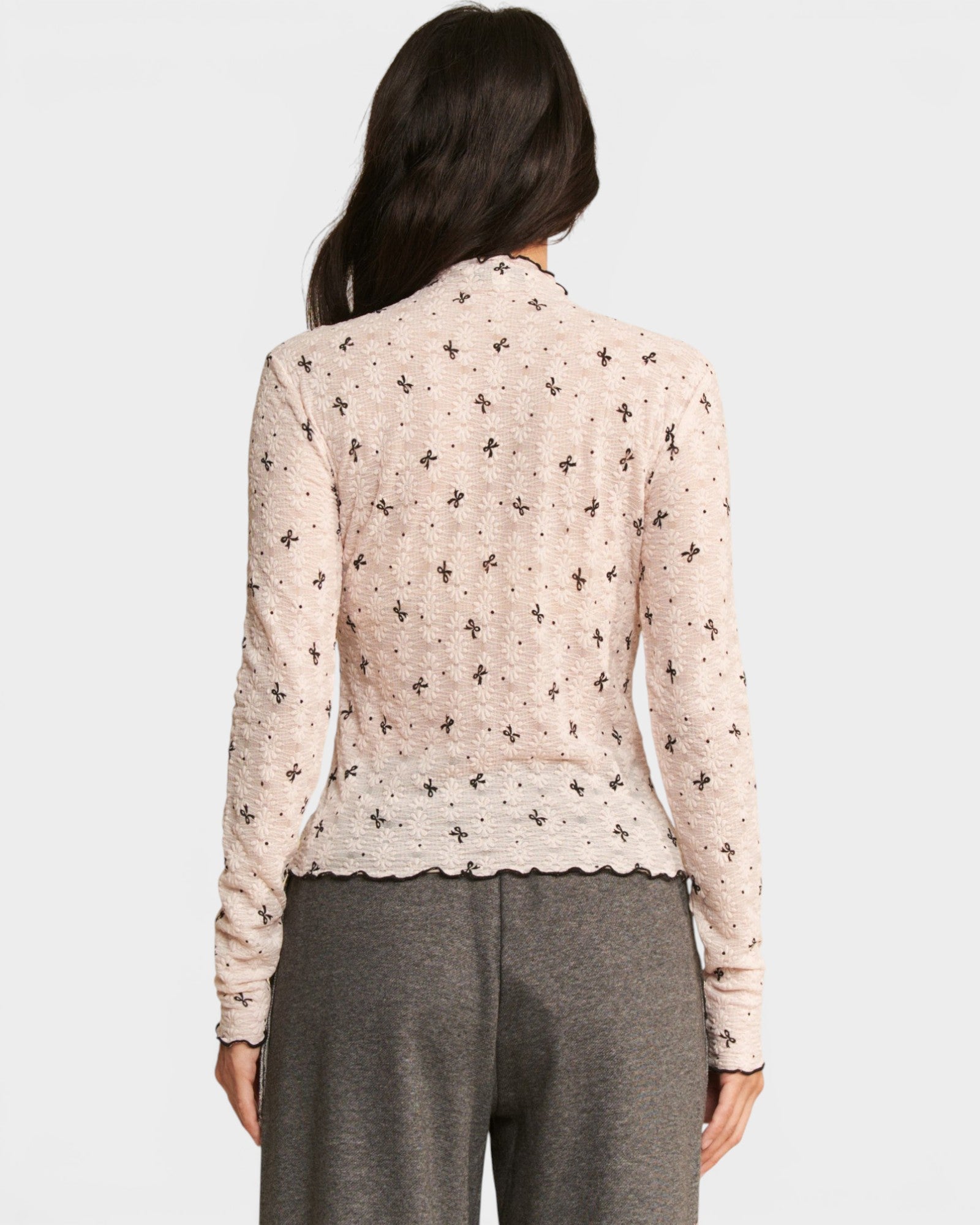 Woman wearing a patterned blouse and gray pants on a white background