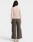 Person wearing a light pink floral blouse and gray wide-leg pants on a white background