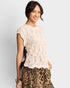 Woman wearing a beige lace top and leopard print pants on a light gray background