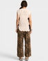 Person wearing a beige sleeveless top and leopard print pants on a white background