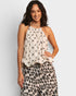 Woman wearing a patterned top and leopard print pants on a plain background