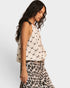Woman wearing a patterned top and leopard print skirt on a white background