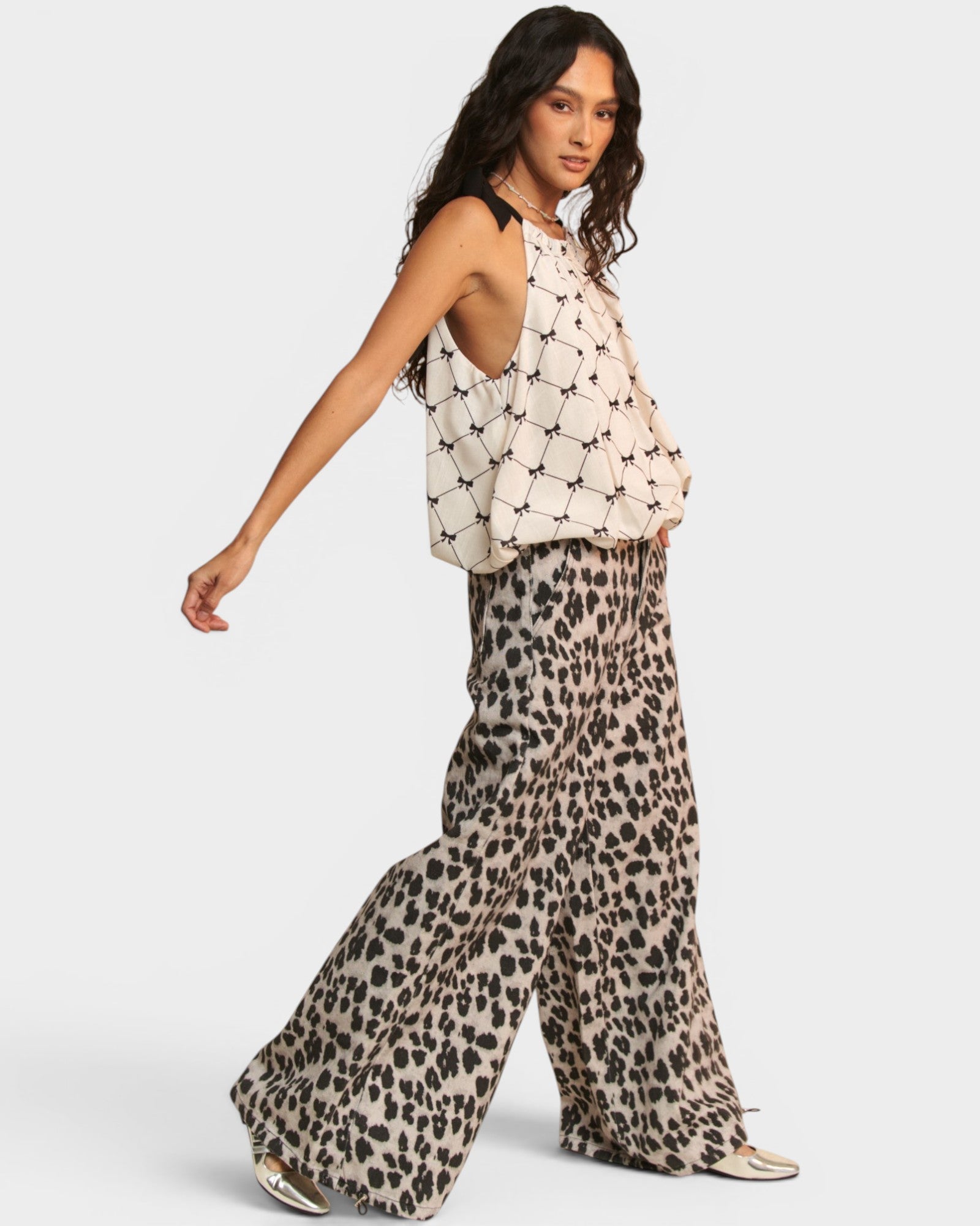 Woman wearing a patterned top and leopard print pants on a white background
