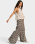 Woman wearing a patterned top and leopard print pants on a white background
