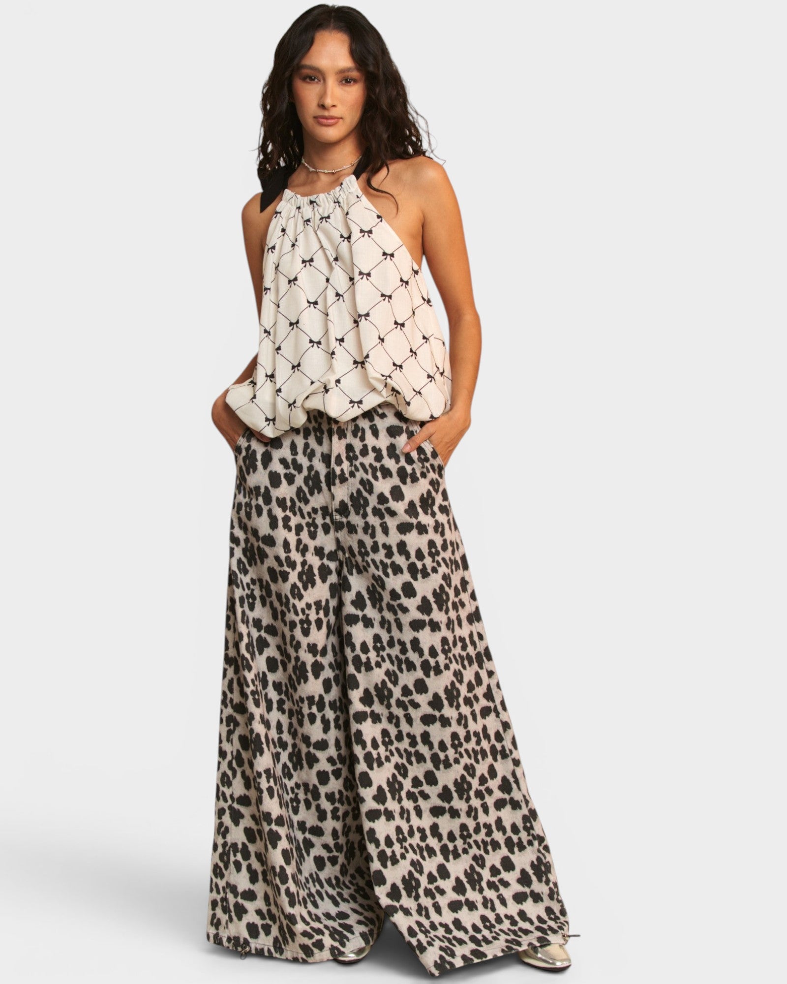 Woman wearing a halter top and leopard print pants on a white background
